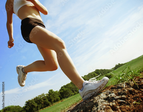 Photo: Beautiful woman runner in front of blue sky, low angle. Beautiful woman runner in front of blue sky, low angle.