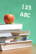 An apple on a stack of books on the teachers desk