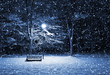 View of bench and shining lantern through snowing. Night shot..
