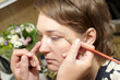 A cosmetologist applies eyeshadow for a girl