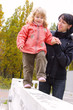 Mother supporting little daughter walking on white railing