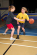 Two female basketball players scrimmage in school gym.