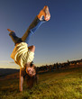Young girl doing cartwheel across green grass