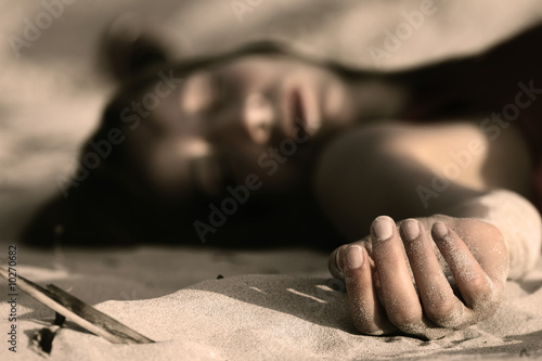 Photo: woman playing dead, lying in the sand woman playing dead, lying in the sand