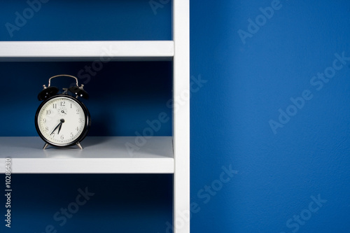 Photo: Green apple and clock inside white bookcase in blue room Green apple and clock inside white bookcase in blue room