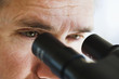 close up of man's eyes looking through microscope.