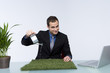 Businessman watering grass and smiling