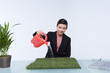Photo: Beautiful business woman watering grass Beautiful business woman watering grass