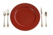 Table setting with red plate and silverware on white