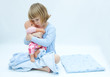girl in bed, hugging her baby doll