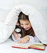 girl reading under blanket with flashlight