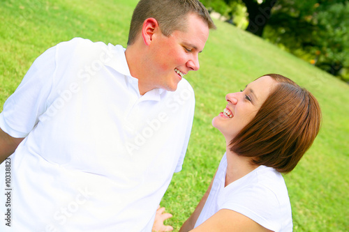 Photo: happy couple embracing in the park. young family happy couple embracing in the park. young family
