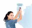 Portrait of a young woman roller painting a wall