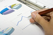 hand with pen showing report with diagrams