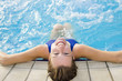 Portrait of young woman sitting in swimming pool, rear view.
