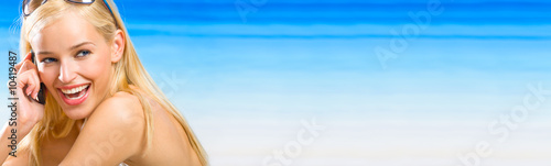 Young beautiful blond woman with cellphone on the beach