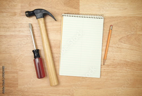 Photo: Notepad, Pencil, Hammer, Screwdriver on a Wood Background. Notepad, Pencil, Hammer, Screwdriver on a Wood Background.