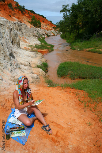 Photo: young woman painting a picture near brown stream young woman painting a picture near brown stream