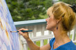 A female artist painting on canvas on her studio balcony