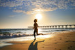 Photo: Woman at the beach running by the ocean at sunset Woman at the beach running by the ocean at sunset