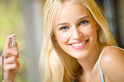 Young happy smiling woman with perfum bottle indoors Young happy smiling woman with perfum bottle indoors
