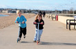 Young brother and sister scooting along a promenade