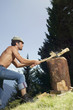 Young man chopping wood, side view