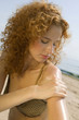 Young woman applying sun cream on beach, close-up