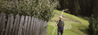 Senior man standing in garden with rake over shoulder