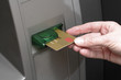 Hand pushing credit card into cash terminal, close-up