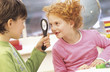 Boy and girl (7-9) fooling around with magnifying glass