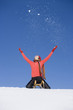 Woman sitting on sledge, lifting arms up