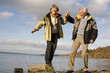 Senior couple by sea, woman standing on wood, smiling