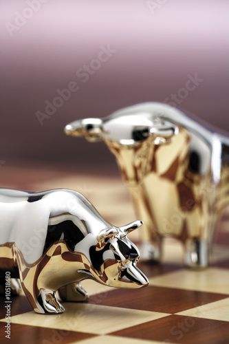 Photo: Bull and bear figurine on chessboard, close-up Bull and bear figurine on chessboard, close-up