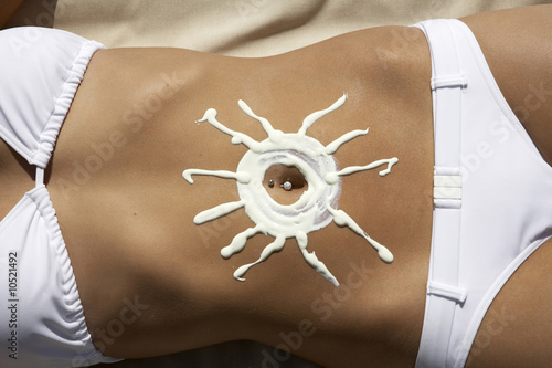 Photo: Woman with sun-shaped sun creme on belly Woman with sun-shaped sun creme on belly