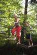 Teenage girl and boy walking on rope bridge, low angle view