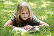 Girl (13-14) lying on grass reading, smiling