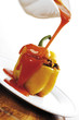 Pouring tomato sauce on bell pepper filled with minced meat, tilt view