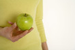Young woman holding apple, mid section, close-up