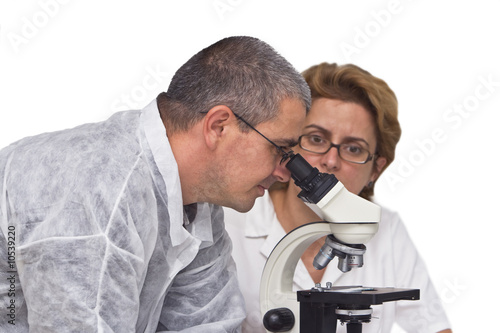 Two researchers working together with a microscope.
