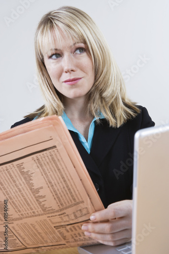 Photo: Businesswoman Reading Stock Listings in Newspaper Businesswoman Reading Stock Listings in Newspaper