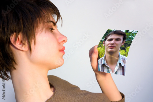 Photo: young woman looking at a picture of a man young woman looking at a picture of a man