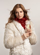 Young beautiful woman in white fur coat with glass of сhampagne