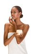 Afro-American girl wrapped in towel putting cream on face Afro-American girl wrapped in towel putting cream on face