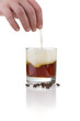 Hand rührt mit Strohhalm Cocktail um