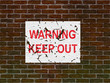 Faded and worn warning poster on an old brick wall