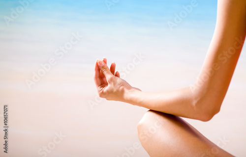 Photo: Young woman doing yoga moves or meditating on beach Young woman doing yoga moves or meditating on beach