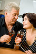 Senior happy couple celebrating with red wine at kitchen