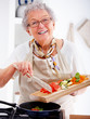 Friendly older woman happily cooking a meal Friendly older woman happily cooking a meal