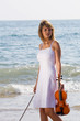 young woman walking on beach with violin